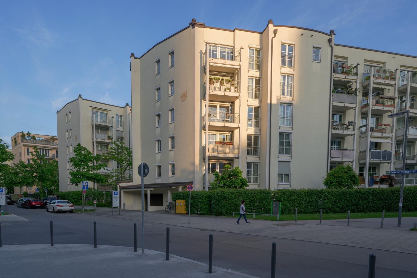 Cream apartment building with plant-filled balconies in late sun.